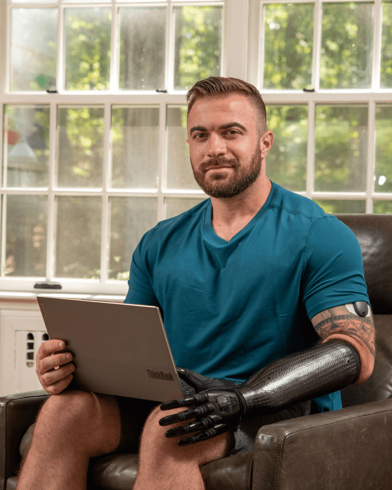 Ein Benutzer des Eversense CGM Geräts erklärt die Vorteile des Transmitters, während er auf einem Stuhl sitzt.